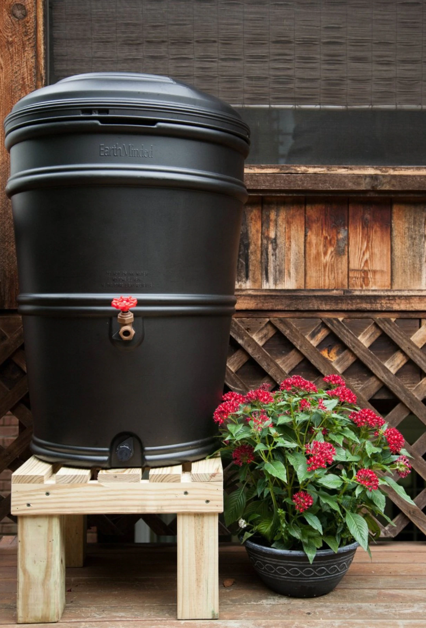 A black rain barrel with a flwe pot